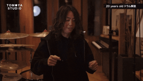 a man playing drums in a room with the words tomoya studio on the bottom