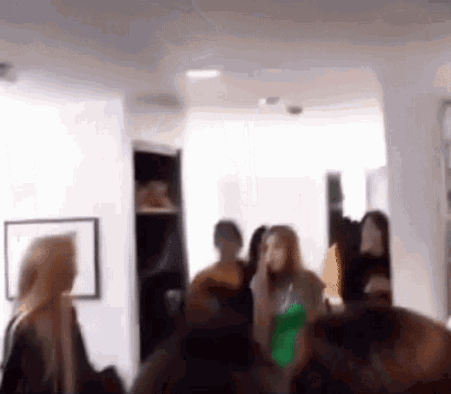 a group of people are standing in a room and talking .
