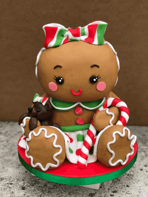 a gingerbread girl with a bow on her head is sitting on a cake