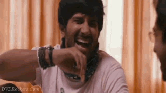 a man with a bandana around his neck is laughing in front of a dvdrockers.com sign