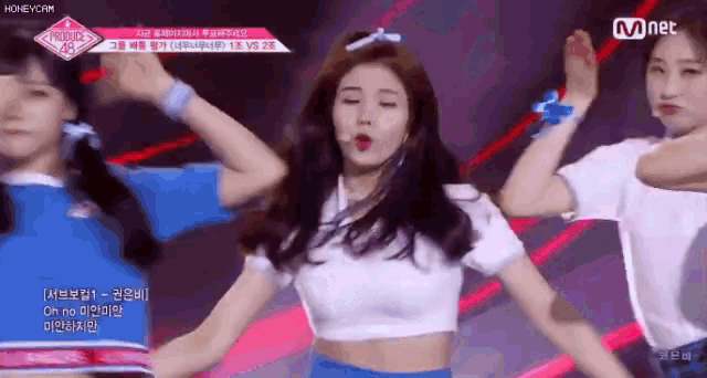 a girl in a white crop top is dancing on stage .