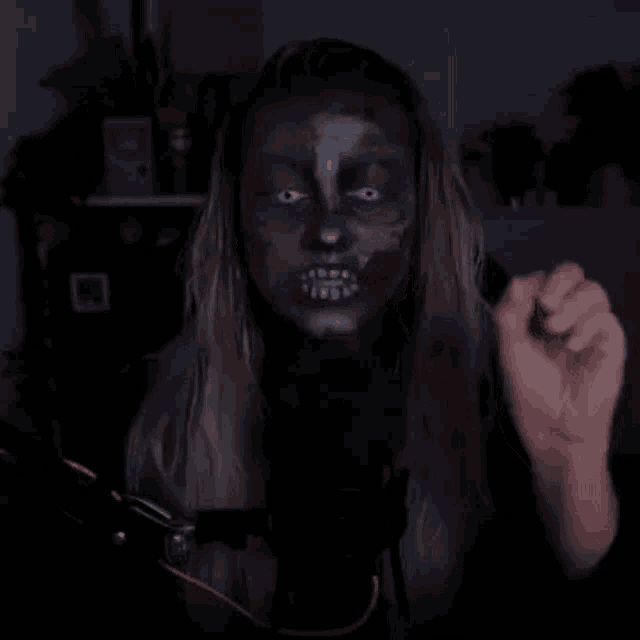 a woman with a skeleton face painted on her face is talking into a microphone