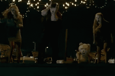 a group of people standing around a teddy bear in a dark room