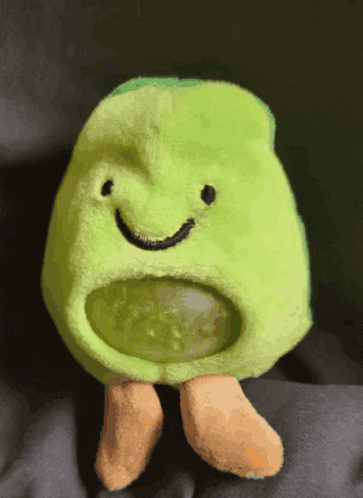 a green stuffed animal with a smiley face on it 's face