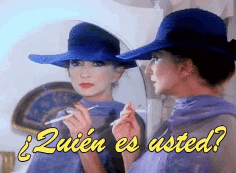 a woman in a blue hat is smoking a cigarette and looking at her reflection in the mirror .