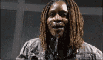 a man with dreadlocks and a beard is standing in a dark room with his mouth open