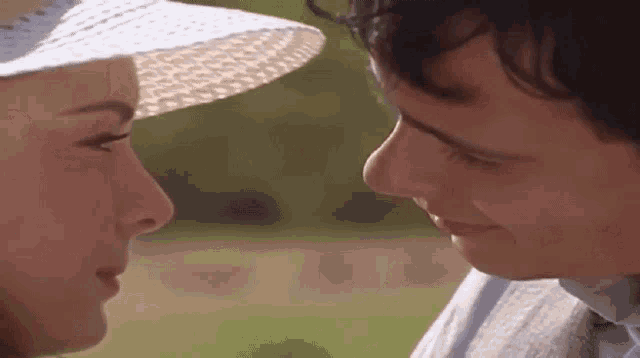 a man and a woman are looking at each other . the woman is wearing a straw hat .