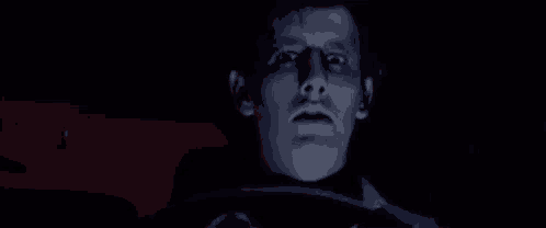 a man is driving a car in the dark and his face is glowing in the dark .