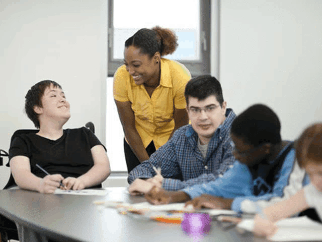 a woman in a yellow shirt talks to a group of young people