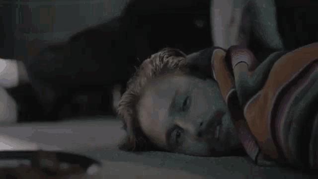 a man is laying on the floor wrapped in a striped blanket .