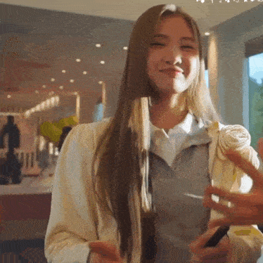 a woman with long blonde hair is smiling and holding a cell phone in her hand .