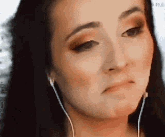 a close up of a woman wearing headphones making a sad face .