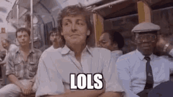 a man is sitting on a bus with his arms crossed and the word lols on his face .
