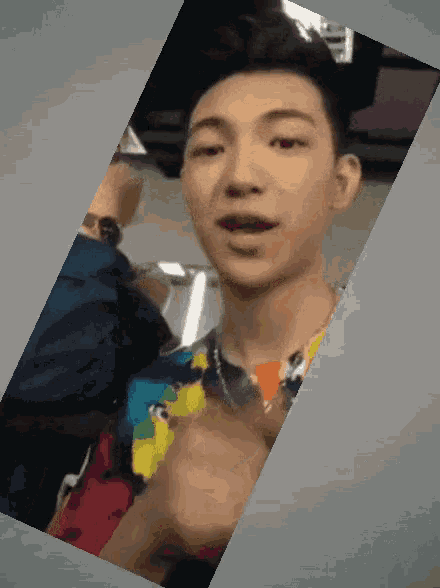 a man in a colorful shirt is pointing to the camera
