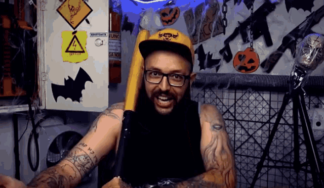 a man with a beard and glasses is holding a baseball bat in front of a sign that says safety first