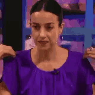a woman in a purple shirt is talking on a television show .