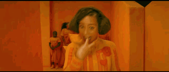 a woman wearing a yellow sweater with the letter t on it