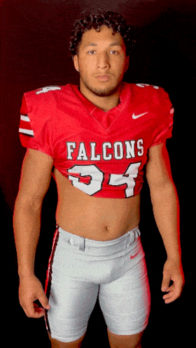 a man in a red falcons jersey stands in front of a black background