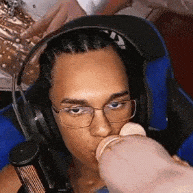 a man wearing headphones is drinking from a baby bottle .