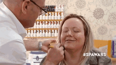 a man is putting makeup on a woman 's face .