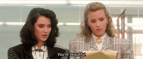 two women are standing next to each other in a room and talking .