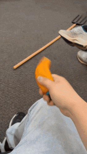 a person is holding a piece of orange in their right hand