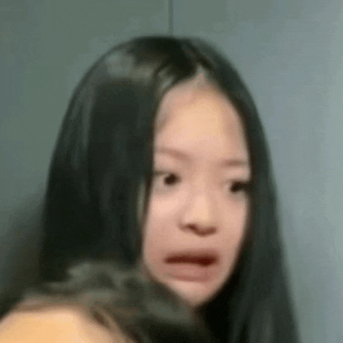 a young woman with long black hair is making a funny face .