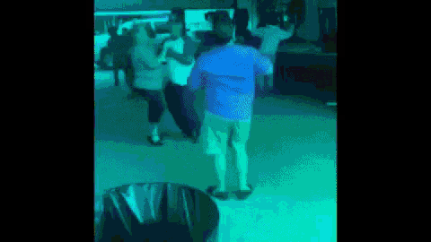 a man in a blue shirt is dancing in a dark room