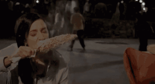 a woman is eating a corn on the cob in a dark room .