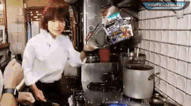 a woman is cooking on a stove in a kitchen