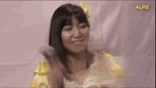a woman in a yellow dress with the word alfie on the bottom left