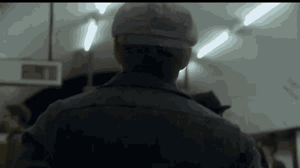 a man wearing a hat is standing in a dark room .