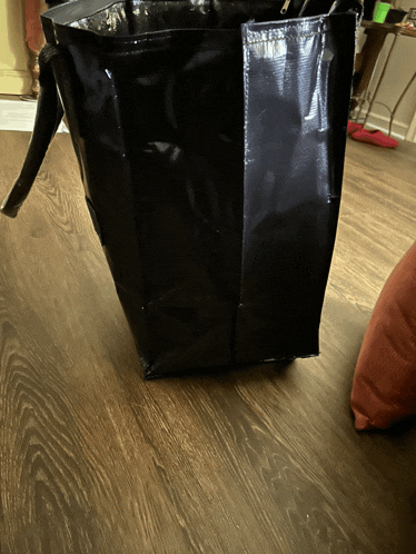 a black plastic bag is sitting on a wood floor