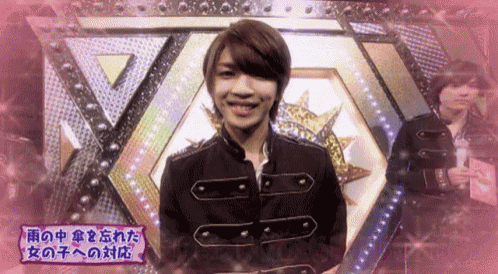 a man in a black jacket is smiling in front of a pink background with chinese writing on it