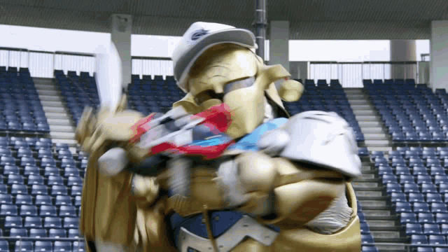 a man in a knight costume is holding a sword in a stadium with blue seats