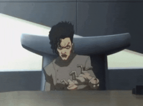 a cartoon character is sitting at a table with a t on his shirt