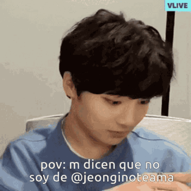 a young man with a blue shirt is sitting in front of a vlive sign .