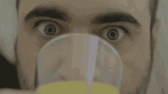 a close up of a man 's face drinking orange juice