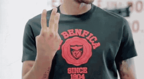 a man wearing a benfica t-shirt is giving the peace sign