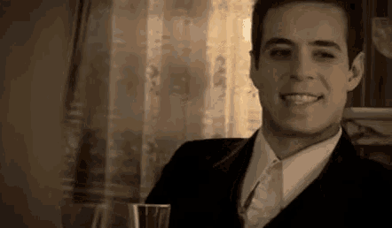 a man in a suit and tie is holding a glass of wine .