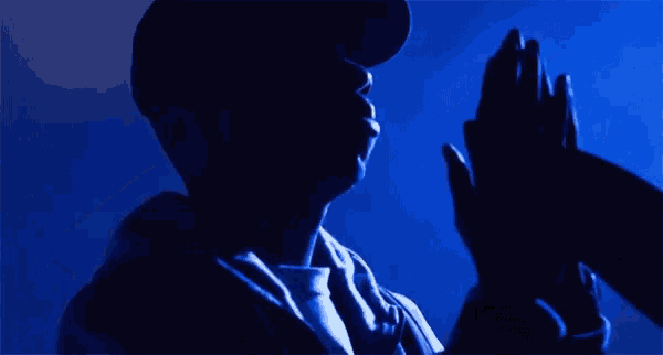 a man wearing a hat and a jacket is standing in a dark room .