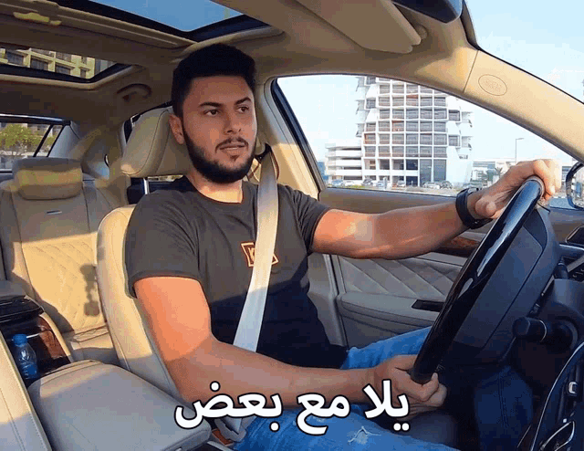 a man is driving a car with arabic writing on the steering wheel