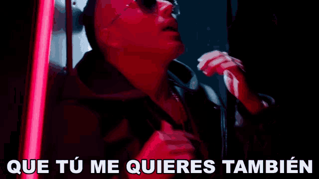 a man wearing sunglasses is looking out a window and the words que tu me quieres tambien are above him