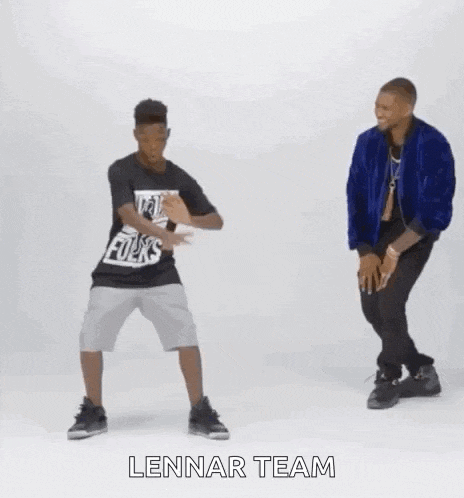 two men are dancing together with their arms in the air and one of them is wearing a blue jacket .