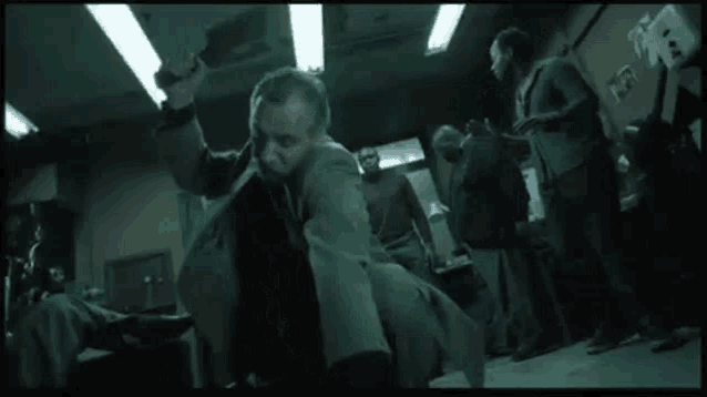a man in a suit is standing in a dark room with a group of people .