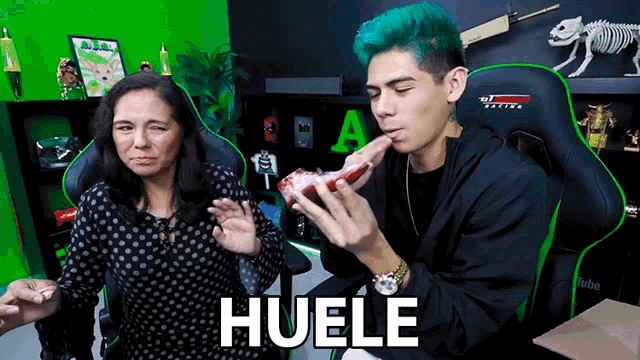 a man with green hair is eating a piece of meat next to a woman who is wearing a black polka dot shirt