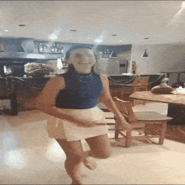 a woman in a blue top and white skirt is dancing