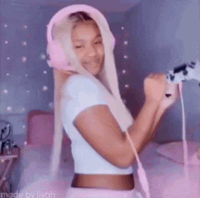 a woman wearing headphones and holding a video game controller is standing in a room .
