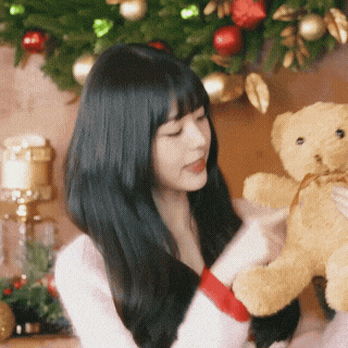 a woman holds a teddy bear with a red ribbon around her wrist