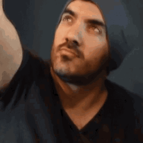 a man with a beard is wearing a black shirt and a blue hat .